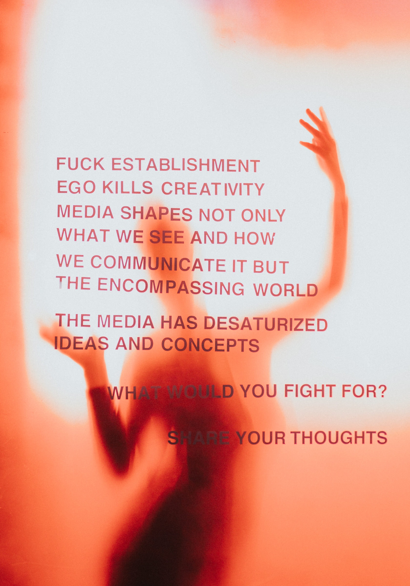 Blurred figure raising an arm behind a manifesto-style text poster in orange tones.