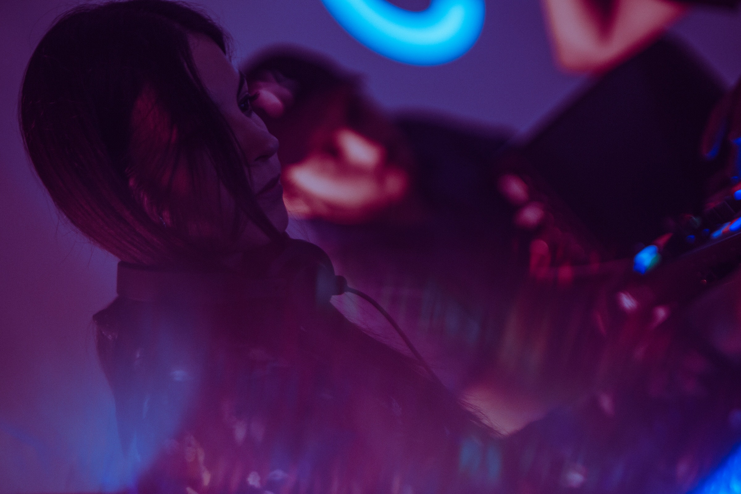 Silhouette of a person lit by neon blue and pink lights at a nightlife event.